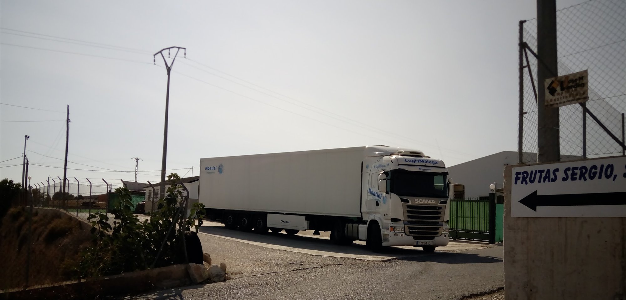Un tráiler frigorífico sale por el portón de Frutas Sergio, junto al cartel de la empresa